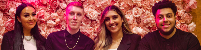 Little Dessert Shop Marketing Team, Simran Mall, Matthew Hillary, Josh Allen, Megan Clarke pose for a photograph in front of a floral back drop in Warrington